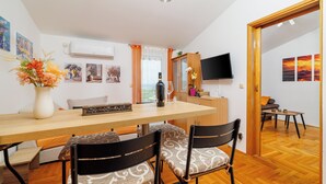 A dining area with a wooden table, chairs, and a vase of flowers. - Apartment with fantastic sea view and balcony in Crikvenica (Crikvenica)