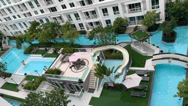 A hotel with multiple swimming pools, a rooftop bar, and lush landscaping. - Luxurious 1-bedroom Condo With Pool Near Jomtien Beach (Pattaya)