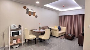 A modern living room with a dining area, a sofa, a coffee table, a TV, and a ceiling light fixture. - Luxurious 1-bedroom Condo With Pool Near Jomtien Beach (Pattaya)