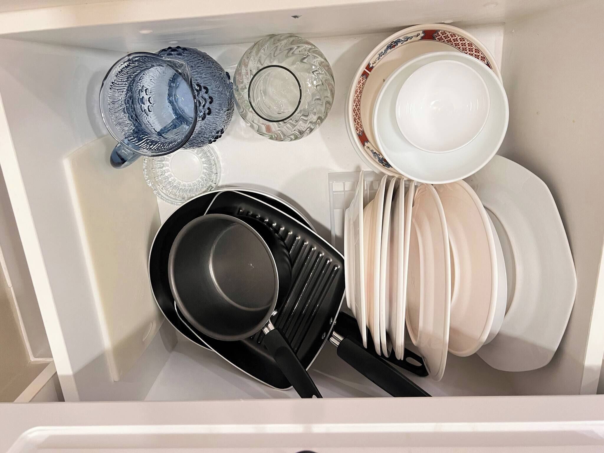A kitchen drawer with various utensils and dishes.