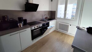 Eine moderne Küche mit Einbauherd, Backofen und Mikrowelle, einem Fenster mit Jalousien und einem Heizkörper.
