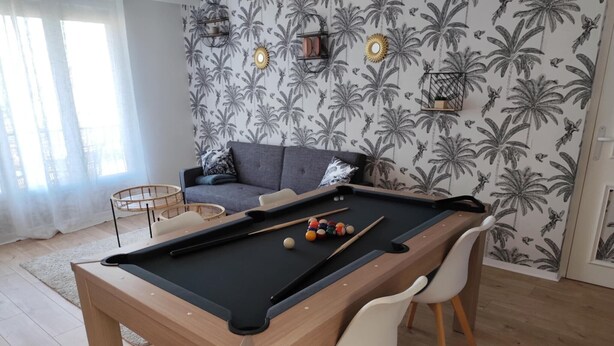 Ein Billardtisch mit Kugeln, eine Couch und eine Wand mit Muster.