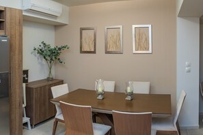 Ein Essbereich mit Holztisch, weißen Stühlen und drei gerahmten Kunstwerken an der Wand.