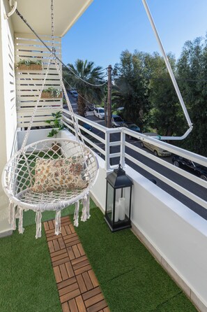 A balcony with a hanging chair, a lantern, and a pathway. - Julia's Apartment (Rodos)