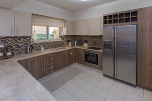A modern kitchen with wooden cabinets, a built-in oven, a stainless steel refrigerator, and a window with a view. - Julia's Apartment (Rodos)