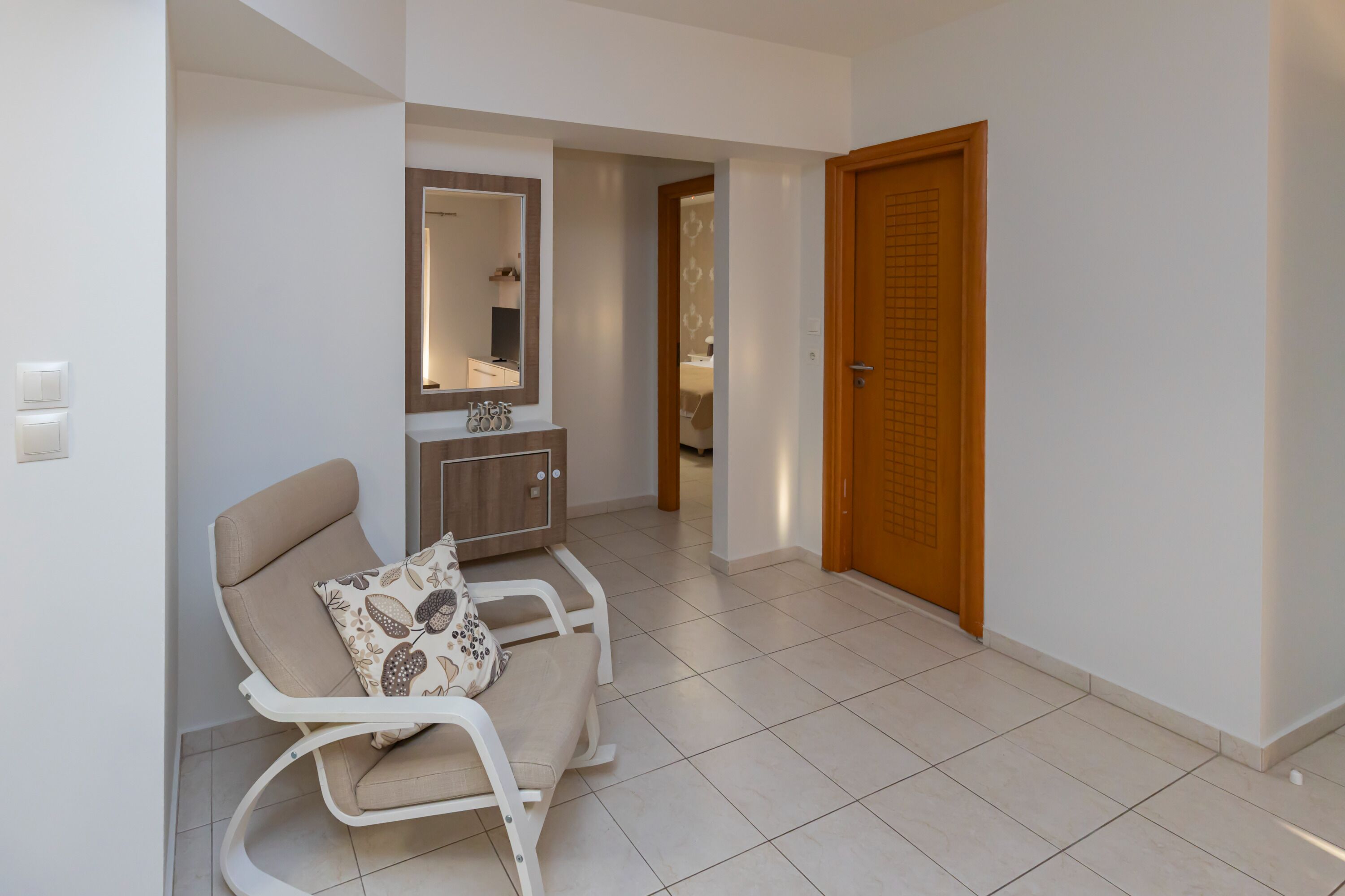 Une pièce avec un canapé blanc, une porte en bois et un miroir au mur.