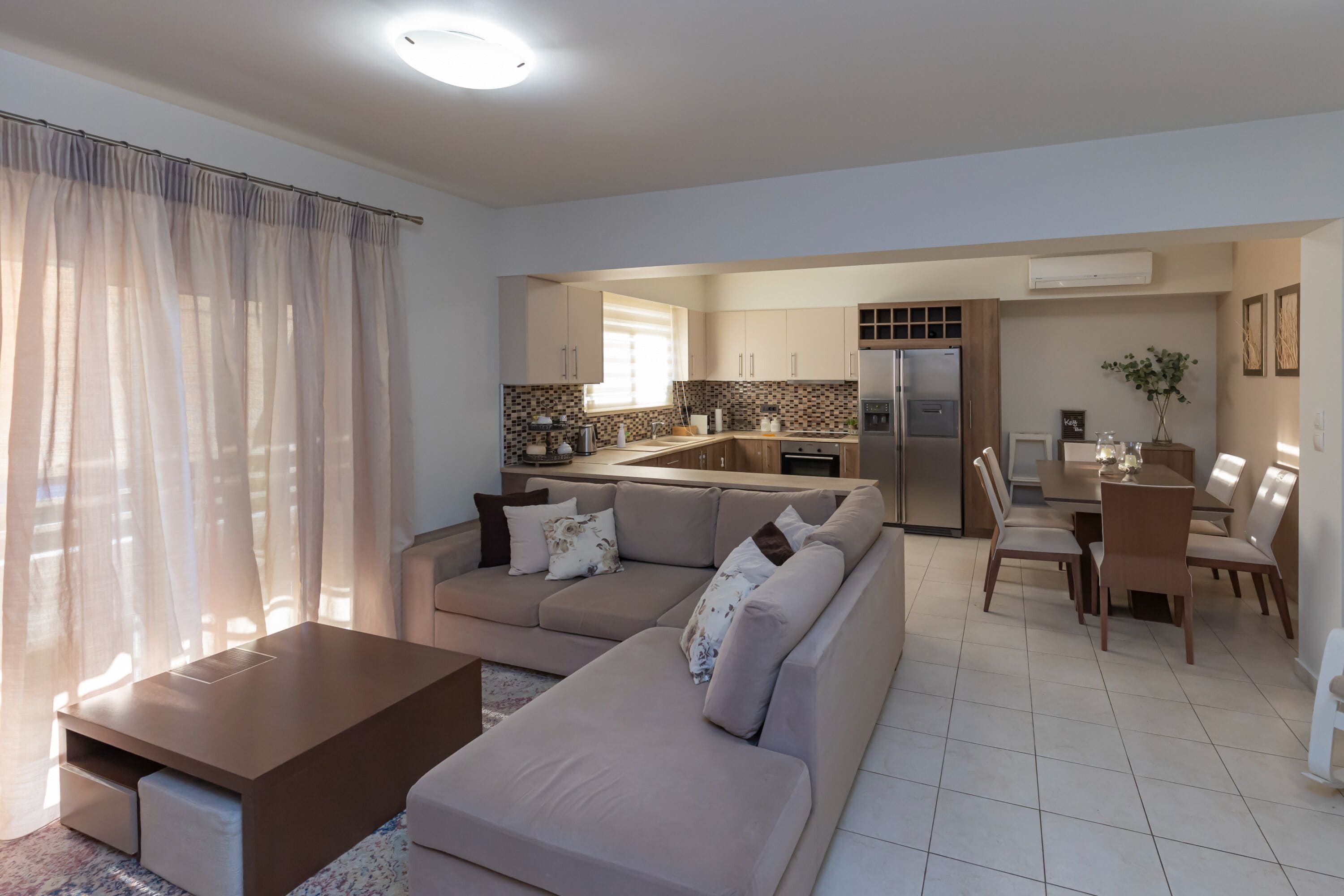 A modern living room with a sofa, a coffee table, and a dining area with chairs and a table.