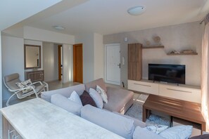 A modern living room with a sofa, TV, and wooden cabinet. - Julia's Apartment (Rodos)