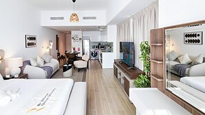 A modern hotel room with a bed, a seating area, a TV, and a kitchen area. - Mayan Building Apartments by RHH (Abu Dhabi)