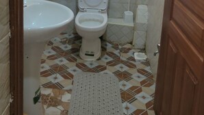 A bathroom with a toilet, sink, shower, and a small window. - Tranquil studio apartment in welcoming Thika neighborhood. (Thika)