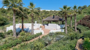 A garden with palm trees, a gazebo, and a white building with steps leading up to it. - Elegant Penthouse Duplex, Sea and Mountain View close to Puerto Banús (Marbella)