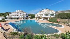 A swimming pool surrounded by white buildings with balconies, a clear sky, and a lifebuoy on the edge. - Elegant Penthouse Duplex, Sea and Mountain View close to Puerto Banús (Marbella)