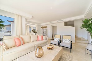 A spacious living room with a beige sofa, two armchairs, a coffee table, and a staircase leading to an upper level. - Elegant Penthouse Duplex, Sea and Mountain View close to Puerto Banús (Marbella)
