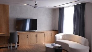 A modern living room with a flat-screen TV, a sofa, a coffee table, and a ceiling fan. - IFQ Premier Skardu (Skardu)
