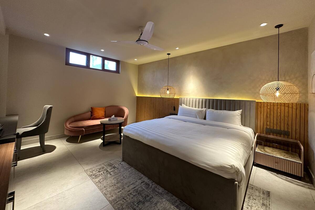 Un dormitorio moderno con cama, escritorio, silla, sofá y ventilador de techo.