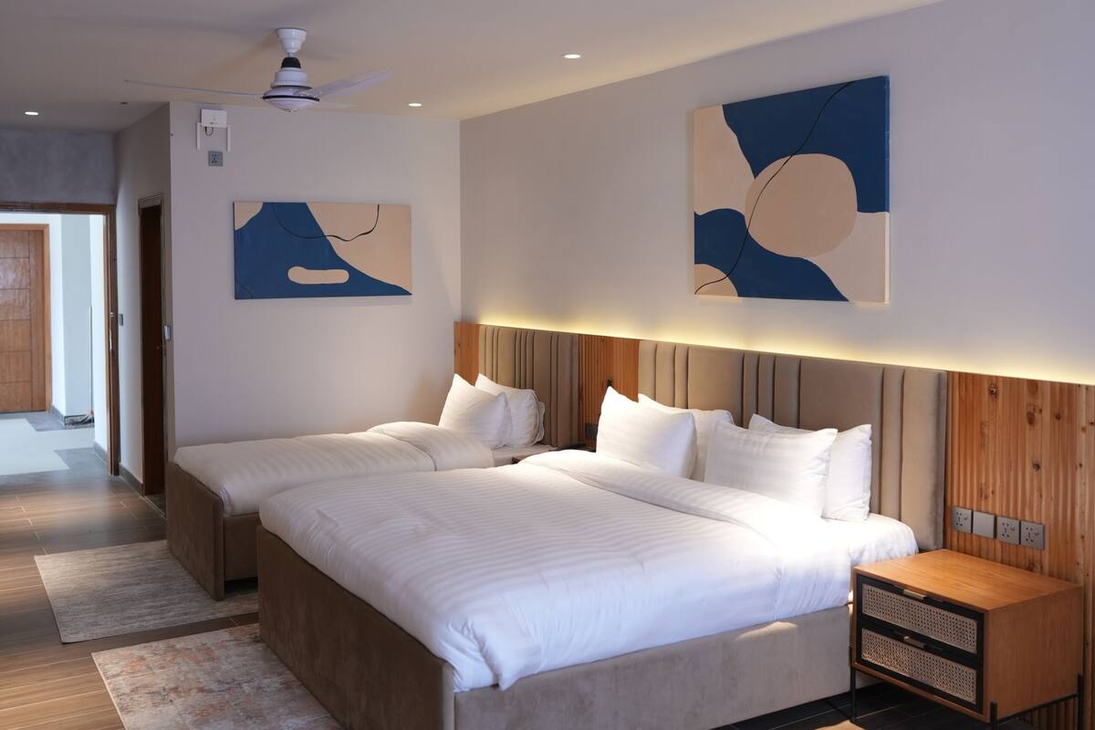 Un dormitorio moderno con una cama grande, cabecera de madera y arte abstracto en la pared.
