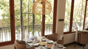 A dining area with a table set for four, large windows, and a hanging light fixture. - IFQ Premier Skardu (Skardu)