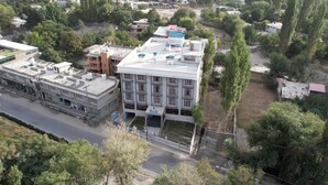An aerial view of a multi-story building with a flat roof, surrounded by trees and other buildings. - IFQ Premier Skardu (Skardu)