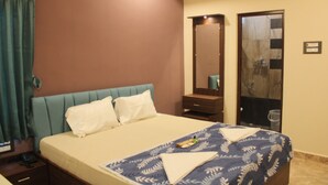 Una habitación de hotel con cama, mesita de noche, espejo y armario.