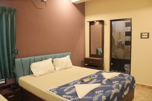 Een hotelkamer met een bed, nachtkastje, spiegel en kledingkast.