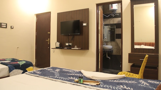Habitación de hotel con cama, televisión montada en la pared, baño con espejo y ducha.