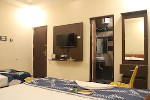 Habitació d'hotel amb llit, televisió penjada a la paret, bany amb mirall i dutxa.