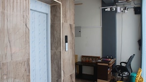 Una habitación con pared de mármol, un escritorio de madera, una silla de oficina negra y un ventilador de techo.