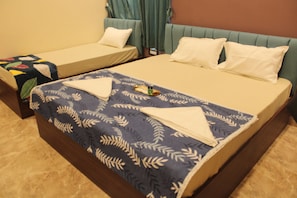 Habitació d'hotel amb dos llits, un edredó blau amb dibuixos i un panell de fusta al capçal.