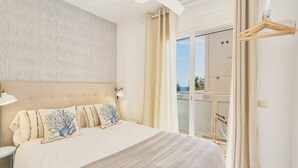 Ein Schlafzimmer mit Bett, Deckenventilator, Nachttisch und Blick ins Freie.