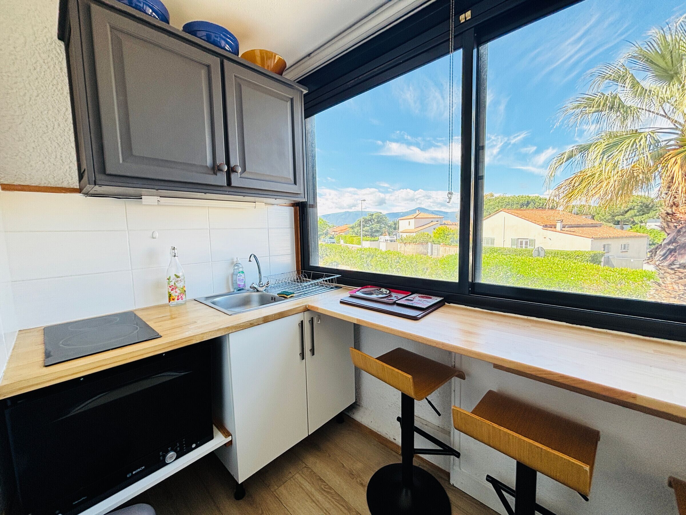 A kitchen with a window view, a Bosch dishwasher, and a wooden countertop.
