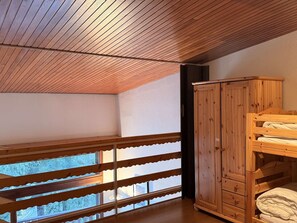 A room with a sloped ceiling, wooden bunk beds, a wardrobe, and a window with a view. - Central apartment, pets welcome - 6 guests, south balcony (Arâches-la-Frasse)