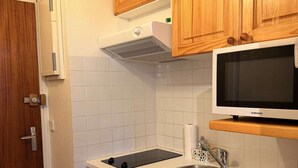 Eine Küche mit integriertem Geschirrspüler, einer Edelstahl-Spüle, einer Mikrowelle, Holzschränken und einer Fliesenk üchenwand.