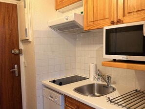 A kitchen with a built-in dishwasher, a stainless steel sink, a microwave, wooden cabinets, and a tiled backsplash. - Central apartment, pets welcome - 6 guests, south balcony (Arâches-la-Frasse)