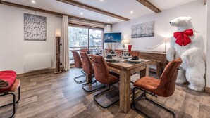 Un coin repas avec une table et des chaises en bois, une grande fenêtre offrant une belle vue et une statue d’ours polaire.