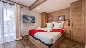 Une chambre à coucher avec un lit, des murs en bois, une fenêtre avec des rideaux et un tableau accroché au mur.
