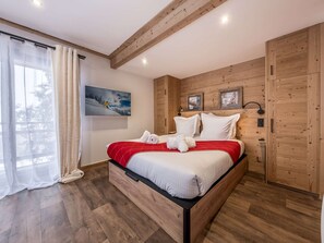 Ein Schlafzimmer mit Bett, Holzwänden, einem Fenster mit Vorhängen und einem Bild an der Wand.