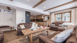 Un salon moderne avec une table basse en bois, deux canapés et un coin cuisine doté de meubles de rangement en bois.