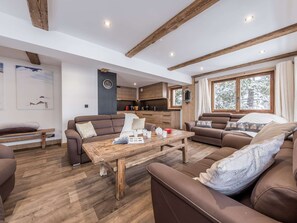 Ein modernes Wohnzimmer mit einem Holztisch, zwei Sofas und einer Küchenzeile mit Holzschränken.