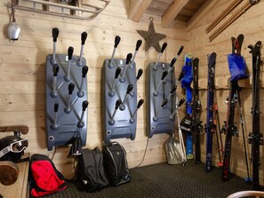 A ski storage area with wall-mounted racks holding ski poles and skis, a star decoration, and a helmet on the floor. - Chalet in Courchevel 1650, 10 people, parking (Courchevel)