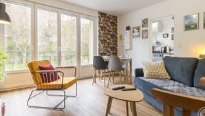 Ein modernes Wohnzimmer mit Sofa, Sesseln, Esstisch und Küchenzeile.