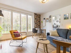 Ein modernes Wohnzimmer mit Sofa, Sesseln, Esstisch und Küchenzeile.
