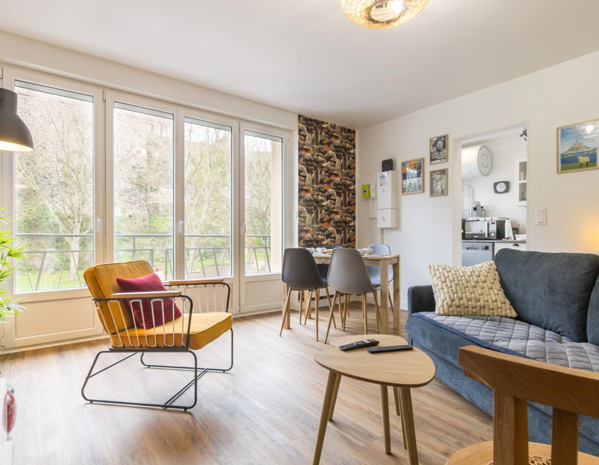 Una sala de estar moderna con un sofá, sillas, una mesa de comedor y una zona de cocina.