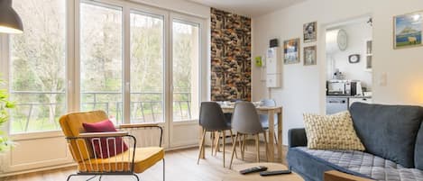 Una sala de estar moderna con un sofá, sillas, una mesa de comedor y una zona de cocina.