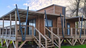A wooden cabin with a covered porch and a staircase leading to a deck.