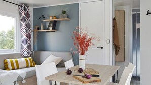 Een moderne eetruimte met een houten tafel, witte stoelen en een vaas met roodloof.