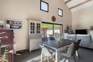 Un espace repas comprenant une table, des chaises et donnant sur lâextĂ©rieur.