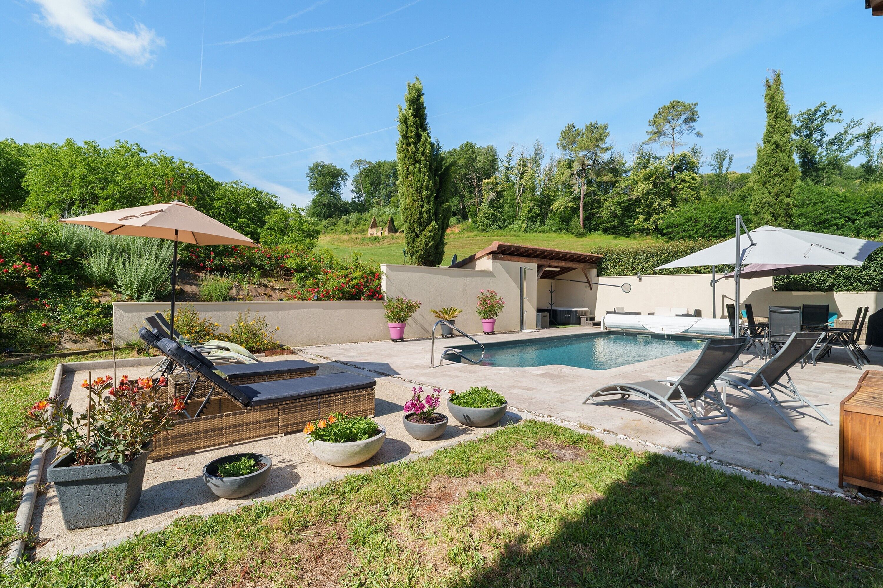 A backyard with a swimming pool, lounge chairs, and potted plants.