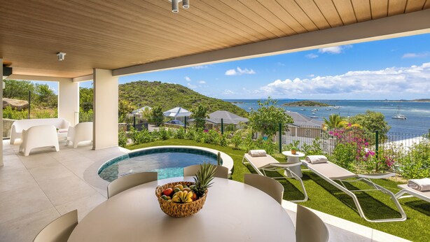 Uma área de piscina moderna ao ar livre, com vista para o mar e as colinas.