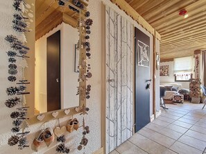 Ein Zimmer mit Holzboden, einem Bett mit Kissen, einem Fenster mit Vorhängen und einer Tür mit Spiegel.