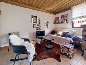 Ein Wohnzimmer mit einer Couch, einem Sessel, einem Fernseher und einem Couchtisch.